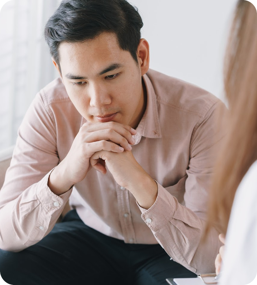 A man sitting down with his hands clasped together.